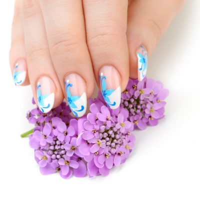 Nail art. Female nails with figure of petal blue color closeup and flower